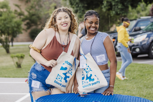 Two female students smiling holding ˿Ƶ Block Party bags